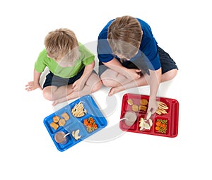 Two young boys eating school lunch on white