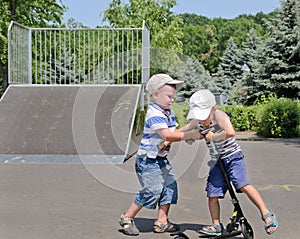 Two young boys fighting over a scooter