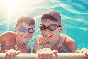 Two young boys holding edge of swimming pool