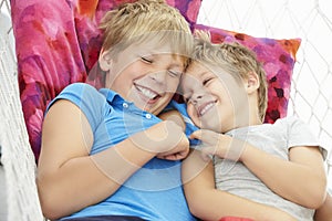 Two Young Boys Relaxing In Garden Hammock Together