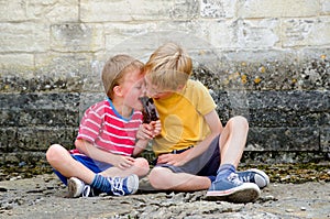 Two young boys sharing a lollipop