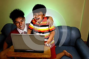 Two Young boys using a laptop computer and smiling