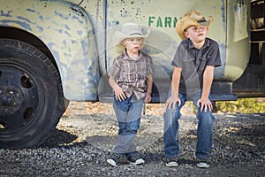 Two Young Boys Wearing Cowboy Hats Leaning Against Antique Truck