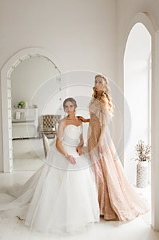 Two young brides in a beautiful dress in bright white studio. Wedding concept.