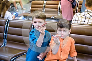 Two young brother boy dreaming of becoming a pilot. A child with a toy airplane plays at airport waiting for departure on their