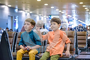 Two young brother boy dreaming of becoming a pilot. A child with a toy airplane plays at airport waiting for departure on their