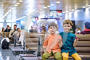 Two young brother boy dreaming of becoming a pilot. A child with a toy airplane plays at airport waiting for departure on their