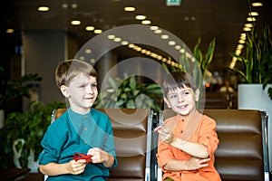 Two young brother boy dreaming of becoming a pilot. A child with a toy airplane plays at airport waiting for departure on their