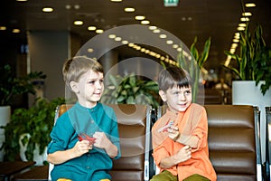 Two young brother boy dreaming of becoming a pilot. A child with a toy airplane plays at airport waiting for departure on their