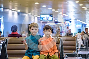 Two young brother boy dreaming of becoming a pilot. A child with a toy airplane plays at airport waiting for departure on their