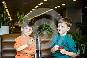 Two young brother boy dreaming of becoming a pilot. A child with a toy airplane plays at airport waiting for departure on their