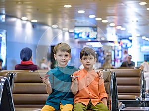 Two young brother boy dreaming of becoming a pilot. A child with a toy airplane plays at airport waiting for departure on their