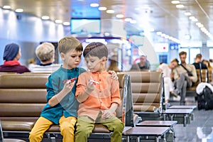 Two young brother boy dreaming of becoming a pilot. A child with a toy airplane plays at airport waiting for departure on their