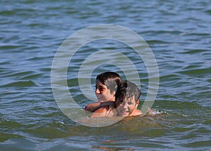 Two young brothers playing in the water of the sea