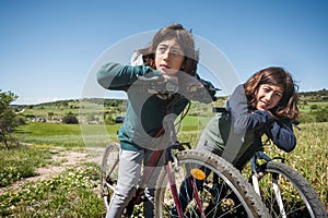 Two young brothers are riding bikes in a field