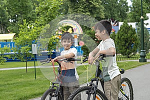 Two young brothers riding their bicycles outside