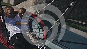 two young brothers swing on a swing on a sunny summer day. Slow motion