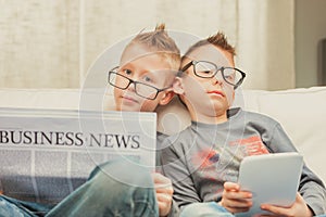 Two young brothers wearing glasses relaxing on a sofa