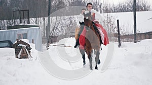 Two young brunettes in a dresses galloping fast on a horse through the snow-covered field in the winter