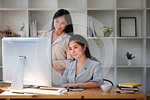 Two young business colleagues analysing financial data on computer at modern office