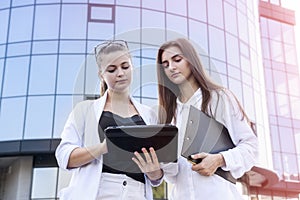 Two young business ladies negotiating near business center