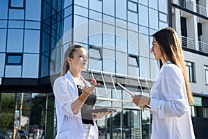 Two young business ladies negotiating near business center