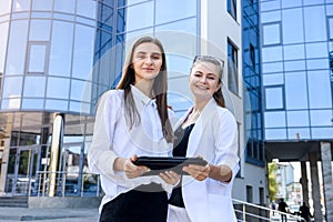 Two young business ladies posing outside office building. Women and business