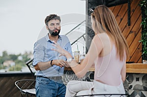 Two young business partners sit outside a busy urban cafe on a cloudy day, discussing growth strategy and expansions.