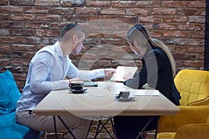 Two young business people brainstorming and discussing business plan on meeting at sunny bright office interior