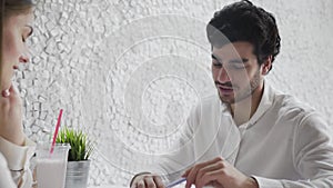 Two young business people sitting for a table while discussing daily business plans use document and graphs