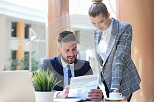 Two young business people using laptop in office while collaborating on startup project