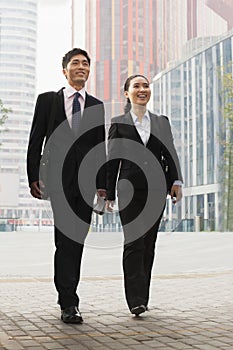 Two young business people walking outdoors, Beijing, China