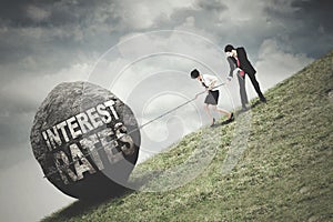 Workers pull a stone with Interest Rates text photo