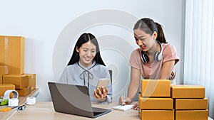 Two young business woman entrepreneur are checking order together on laptop