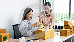 Two young business woman entrepreneur are packing product to parcel box
