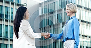 Two young business women shake hands closing a deal in a financial district. Successful women entrepreneurs