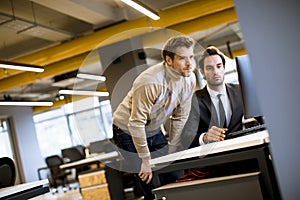 Two young businessmen discussing in office by the table