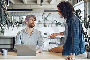 Two young businessmen discussing some ideas in modern office