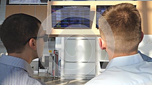 Two young businessmen looking at flight schedule at airport. Business man pointing something to his colleague in