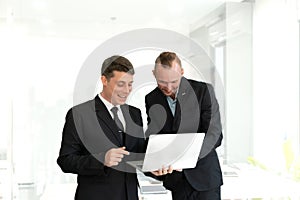 Two young businessmen looking at laptop smiling and expressing joy that the business