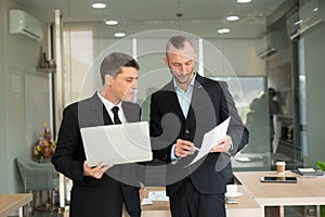 Two young businessmen looking at laptop smiling and expressing joy that the business