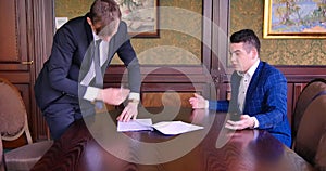 Two young businessmen sign a contract, curse, scream, fight. Office, nerves, torn deal, inappropriate conditions, bad