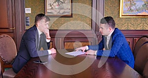 Two young businessmen sign a contract. Start of negotiations, etiquette, courtesy, discuss contract terms. Business