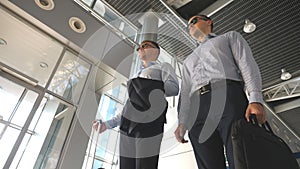 Two young businessmen standing at terminal of airport and talking. Happy caucasian business men having fun during