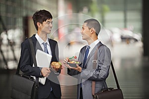 Two young businessmen talking and having a lunch outdoor