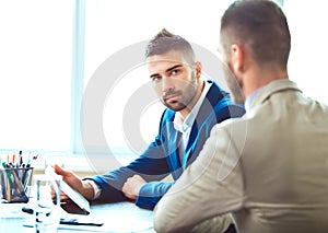 Two young businessmen using touchpad at meeting photo