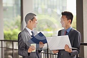 Two young businessmen working outdoor, looking at each other