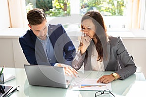 Two Young Businesspeople Analyzing Graph In Office