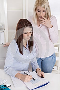 Two young businesswoman at desk looking shocked at balance sheet