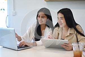 Two young businesswoman working with modern devices and discussing for new project investments.